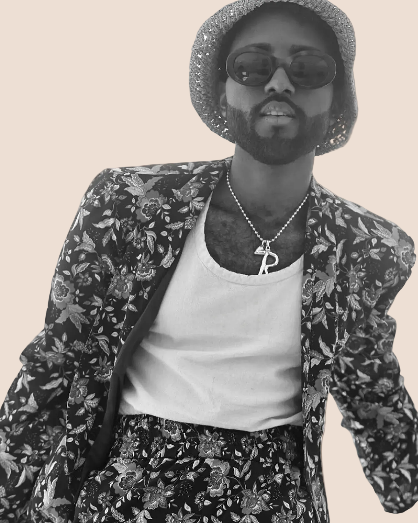 Person wearing a floral jacket and hat with a plain background