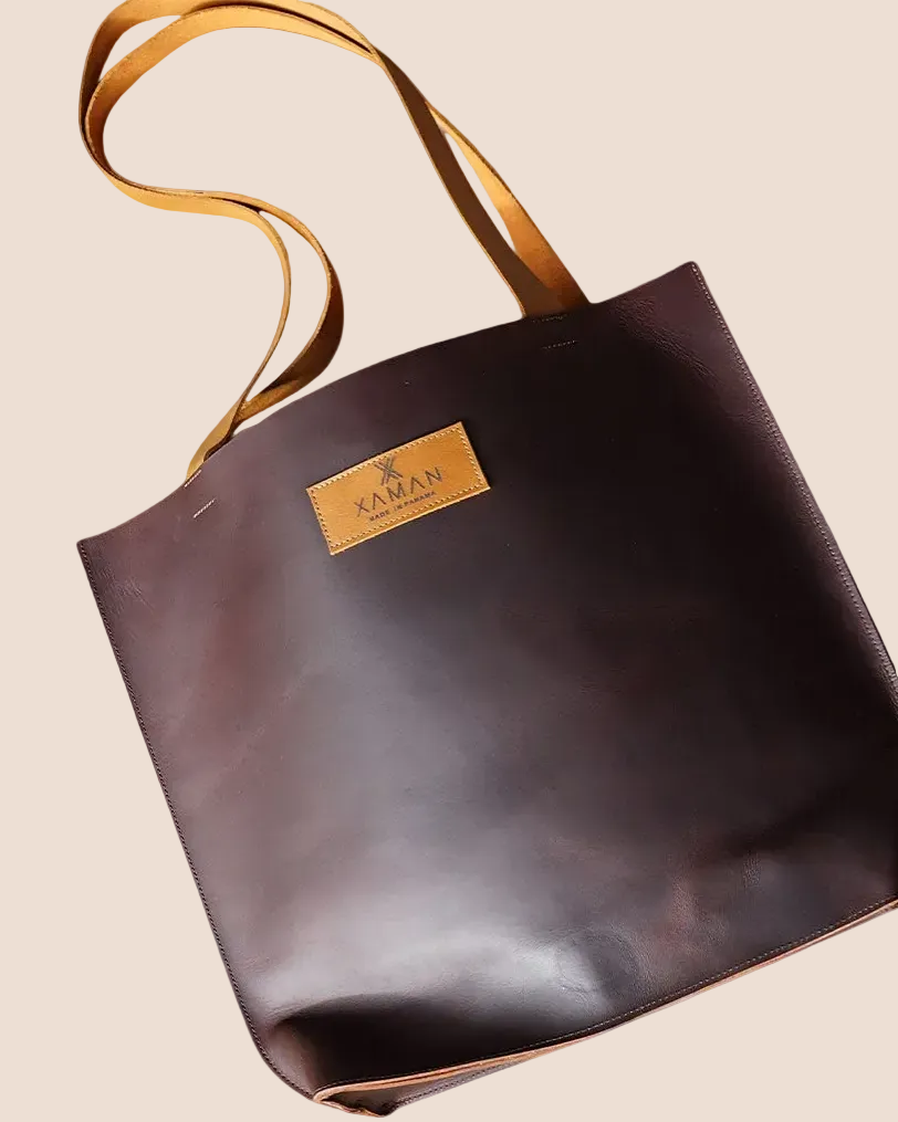 Brown leather tote bag with tan handle on a white background, featuring the Xaman brand.