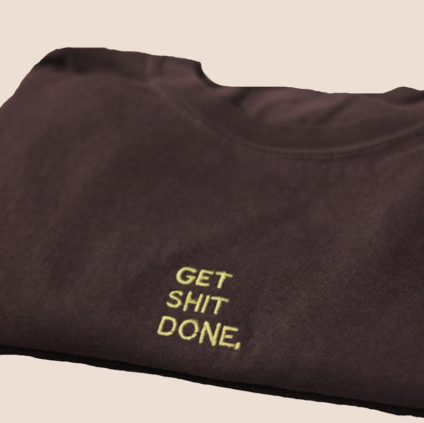 Dark t-shirt with 'GET SHIT DONE.' text on a brown background