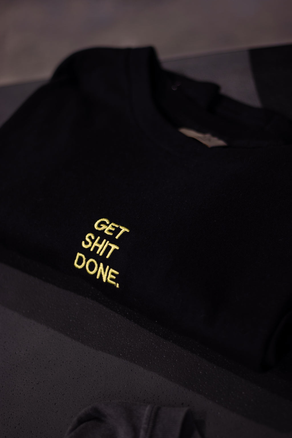 Black sweatshirt with yellow text 'GET SHIT DONE' on a dark background
