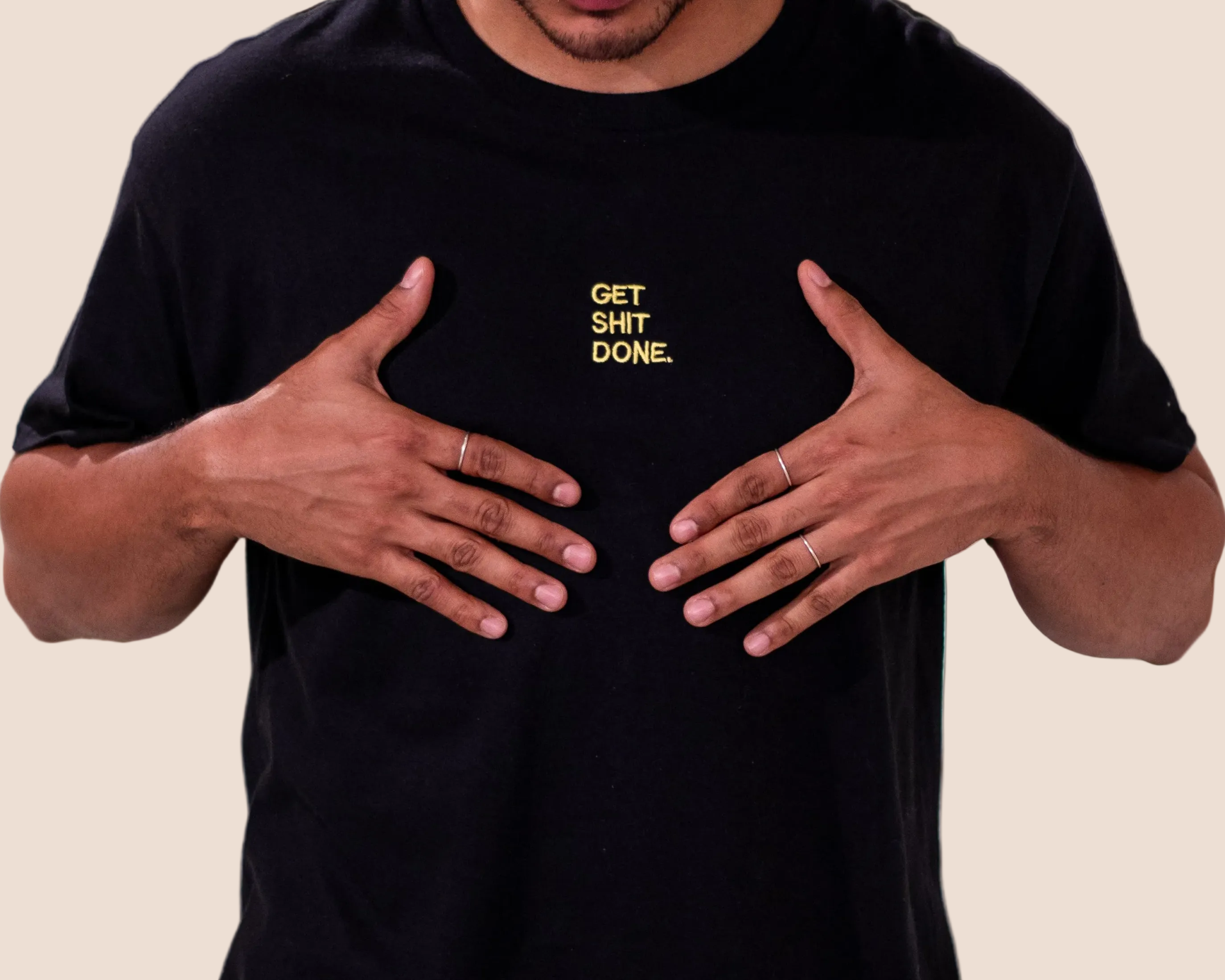Person wearing a black t-shirt with 'GET SHIT DONE' text on a brown background
