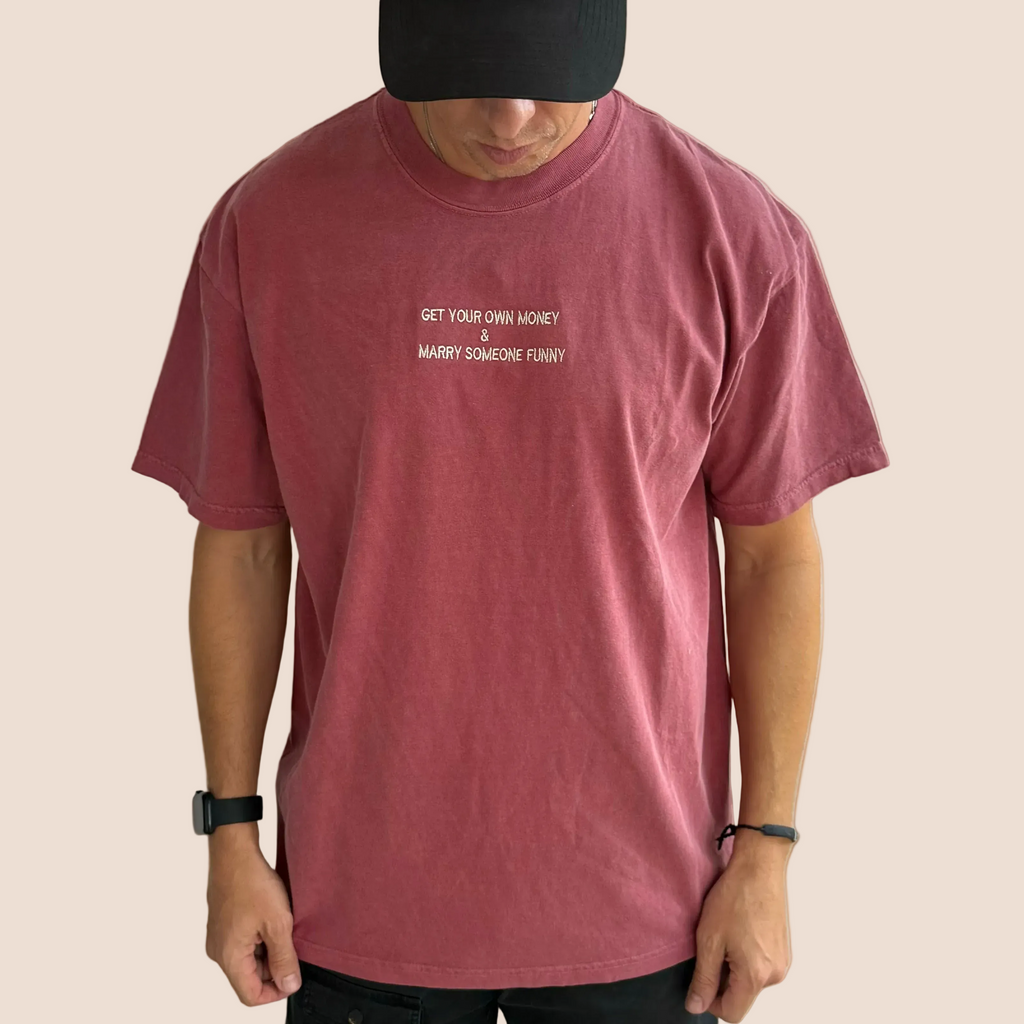 Person wearing a maroon t-shirt with text on a brown background