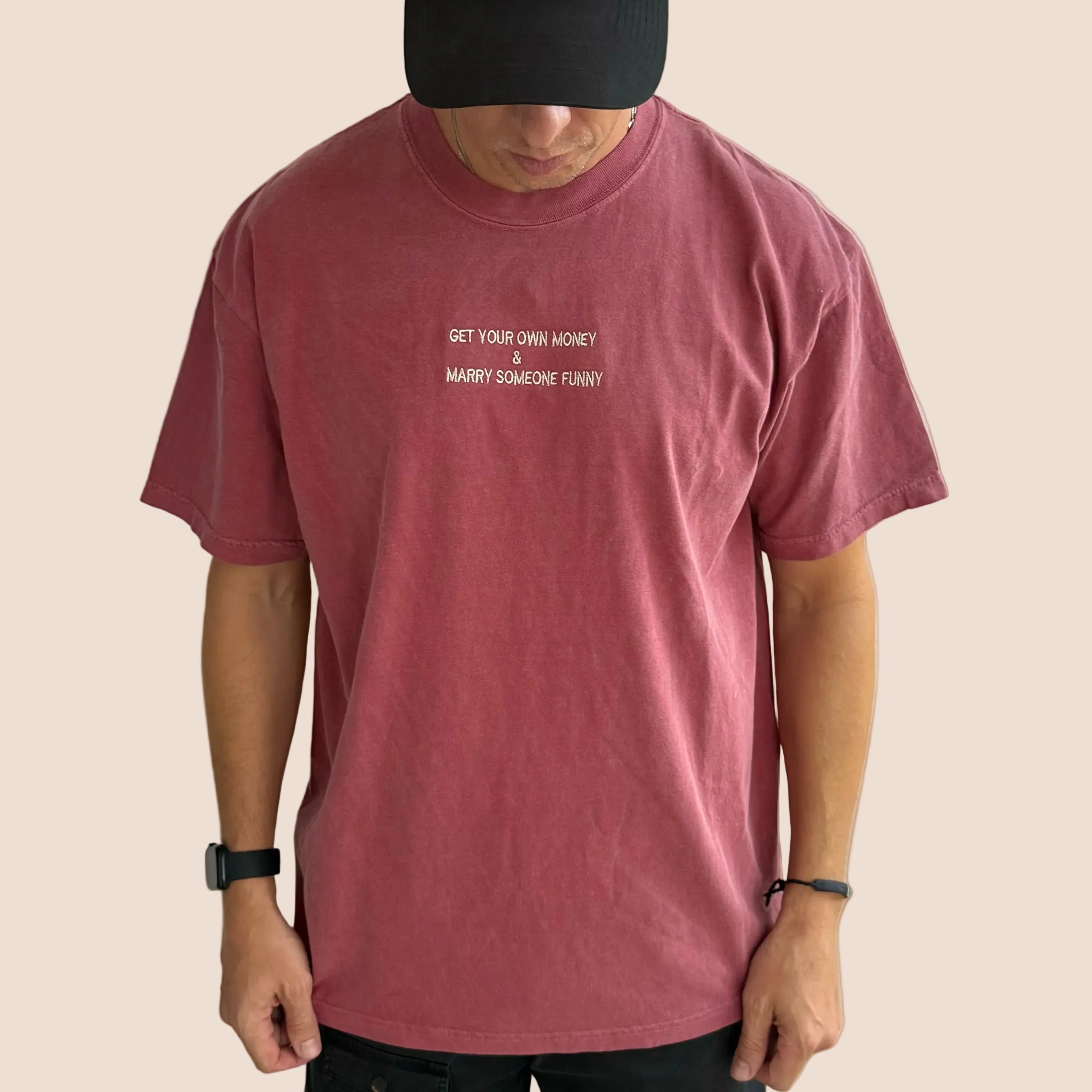 Person wearing a maroon t-shirt with text on a brown background