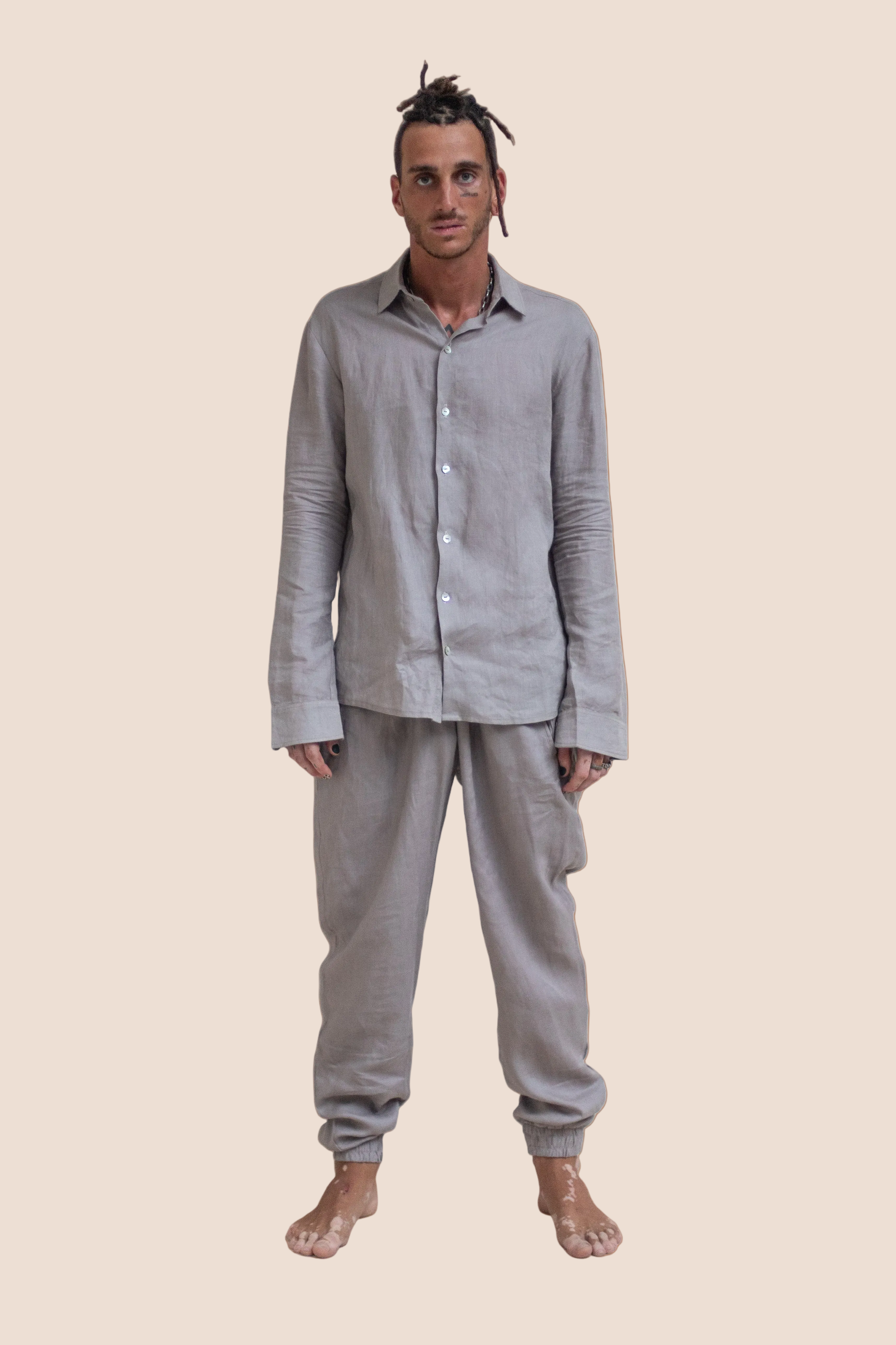 Man wearing a gray shirt and pants on a brown background