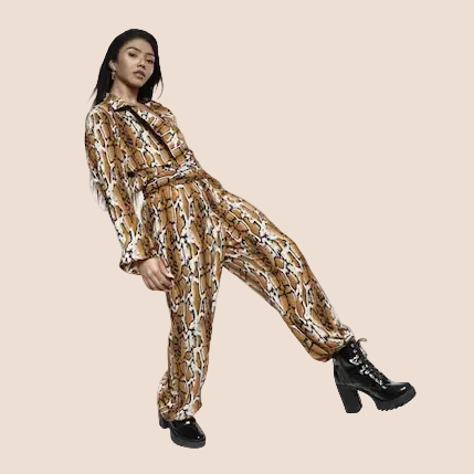 Woman wearing a patterned outfit with black shoes on a brown background