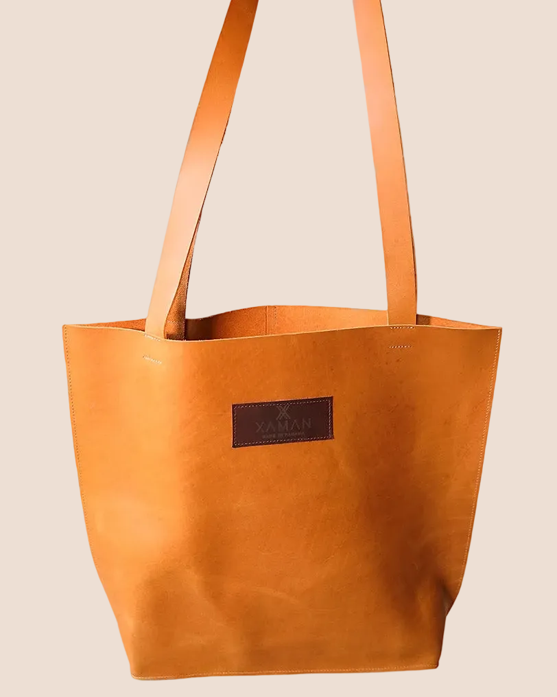 Brown leather tote bag with a visible brand label on a brown background